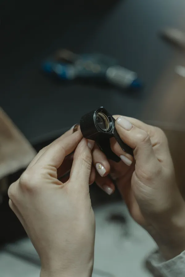 Hands holding a jeweller's loupe up to the light