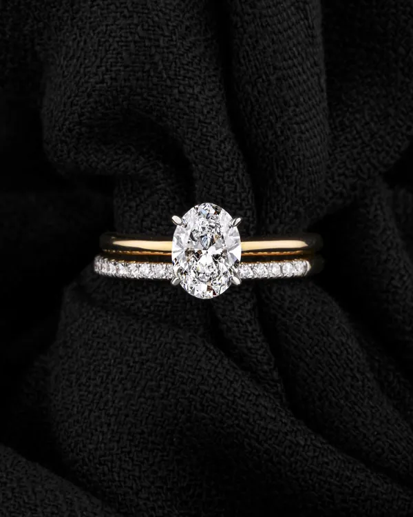 An oval diamond solitaire ring on black fabric