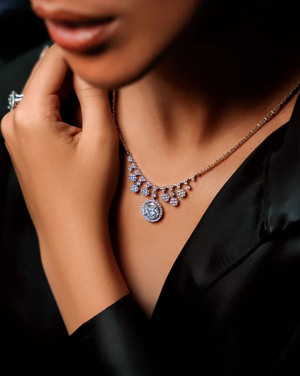 A woman wearing a diamond drop necklace with a black silk top